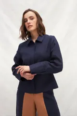 Chaqueta color crema de lino, de corte recto, con cuello camisero y cierre frontal con botones.