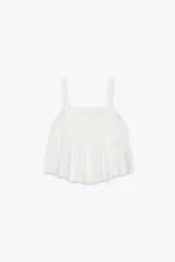 Top blanco de lino con escote recto y tirantes. Presenta detalle de bordados calados y aberturas laterales con lazadas.