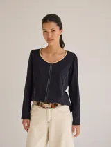 Remera blanca de algodón con escote redondo, mangas largas y pespuntes verticales a contratono.