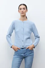 Chaqueta de punto color celeste claro, de manga larga y corte ajustado, con cuello redondo y cierre frontal de botones metálicos plateados. El tejido presenta un patrón texturizado horizontal.