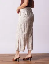 Pantalón crop de lino estampado con hojas en tonos verdes y azules. Tiene pretina trasera elastizada y bolsillos delanteros.