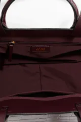 Bolso tipo shopper de cuero sintético con textura de cocodrilo en tono borgoña oscuro. Presenta dos asas de mano cortas y dos asas de hombro largas. La parte superior tiene un borde ondulado.