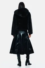 Campera corta de pelo sintético negro, con capucha oversized y cierre frontal oculto con botones a presión. Posee hombros caídos y bolsillos discretos en las costuras laterales. Es forrada.