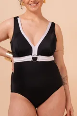 Malla entera negra con escote en V y vivos blancos en contraste. Tiene aplique de aro metálico en el cinto y bolsillo interno en el busto para colocar copa removible o prótesis externa. Confeccionada con tela que contiene fibra LYCRA® XTRA LIFE™.