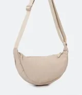 Bolso baguette cruzado color beige, con cierre de cremallera y correa larga regulable.
