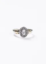 Anillo de plata 925 con diseño de halo, presentando una zirconia central ovalada rodeada por zirconias más pequeñas. El cuerpo del anillo es bicolor, con secciones plateadas y detalles en doublé de oro (baño dorado) a los lados de la piedra principal.