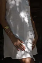 Vestido corto blanco de lino, musculosa con volado en cuello y acceso frontal cruzado. Abotonadura forrada en lino.
