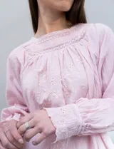 Blusa rosa claro de algodón con escote cuadrado, manga larga y bordado floral en el frente y las mangas.