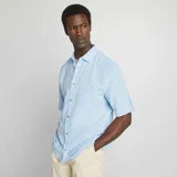 Camisa celeste de lino con corte regular, cuello clásico y manga corta.