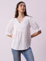 Blusa blanca calada con escote en V, mangas cortas con hombros fruncidos y puños elastizados.