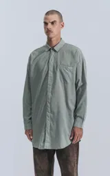 Camisa manga larga gris, de calce oversize con bolsillo ojal en delantero y cartera escondida.
