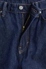 Pantalón de jean azul oscuro de corte holgado, con tiro alto, cinco bolsillos y cierre con botón.