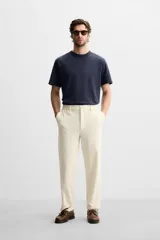 Pantalón color crudo de tejido con textura de rizo, corte relaxed fit, con cintura elástica, bolsillos frontales y traseros, cierre frontal con cremallera y botón.