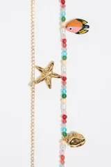 Pulsera de cuentas de colores con dijes dorados de estrella de mar, caracol y tucán.