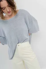 Sweater color crudo de tejido liviano con textura semi traslúcida, escote redondo y mangas amplias estilo murciélago.