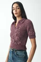 Jersey de punto color borgoña con cuello solapa y escote en pico. Tiene mangas cortas y bordados florales a tono.