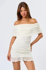 Vestido corto color blanco, con escote off-shoulder, mangas cortas y falda corta con frunces.