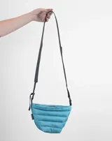 Bandolera celeste acolchada con correa larga ajustable de cinta negra.