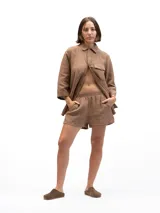 Camisa marrón claro de lino con mangas 3/4, cuello clásico, cierre frontal con botones, bolsillo de parche en el pecho y corte holgado. Marca Gaya.