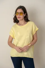 Blusa italiana amarilla combinada con frente de lino y espalda de algodón. Presenta un bordado de plumas al tono en el frente.