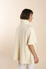 Capa acampanada color beige con manga corta, cierre metálico a la vista, cuello recto, bolsillos con tapa y terminaciones envivadas. Confeccionada en lana fina sin teñir, diseñada exclusivamente por Don Baez.