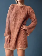 Vestido corto color ladrillo, tejido en algodón y lurex, con espalda descubierta y lazos para atar en la nuca. De manga larga y diseño con ondas.