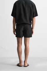 Short de baño negro de tejido técnico, con cintura elástica ajustable con cordón, bolsillos laterales y bolsillo trasero.