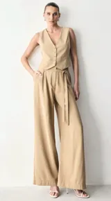 Chaleco color arena de corte sastrero, con escote en V profundo, abotonadura frontal forrada y pinzas que estilizan la silueta.