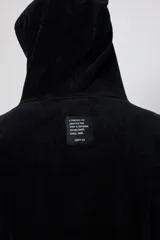 Poncho con capucha confeccionado en tejido de toalla de algodón, color negro, con el logo de la marca Rusty bordado en blanco en el frente.