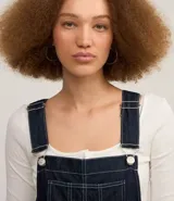 Mono jeans modelo peto confeccionado con algodón más sostenible. La prenda tiene piernas rectas, breteles anchos ajustables, bolsillo en el pecho y costuras contrastantes.