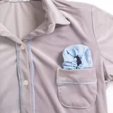 Pijama celeste de terciopelo, compuesto por una camisa de manga larga con botones y vivo blanco, bolsillo en el pecho y un pantalón recto con elástico en la cintura.