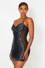Vestido corto negro ajustado al cuerpo, con breteles finos y escote en V. Presenta detalles de strass plateados en el busto y en todo el frente. Tiene paneles de tul transparente en los laterales.