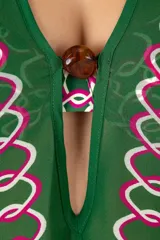 Kaftán largo verde oscuro con patrón geométrico en rosa y blanco, semi-traslúcido, con mangas amplias y escote en V con aplique central.