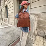 Mochila de eco cuero color marrón, con diseño estructurado y bolsillo frontal con cierre.