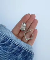 Aros de acero plateado, uno con forma cuadrada y otro con diseño labrado.