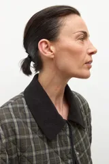 Campera capitoneada con diseño acolchado y estampado a cuadros en tonos verde oliva. Presenta un cuello de pana en color negro, cierre frontal de botones y bolsillos delanteros con ribetes oscuros.