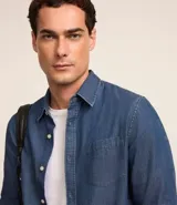 Camisa de hombre de tejido plano de algodón, color celeste claro, con cuello solapa, manga larga y bolsillo simple en el pecho izquierdo.