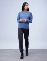 Buzo de tejido melange color beige con puntos oscuros, cuello redondo y manga larga.