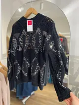 Sweater tejido negro con cuello redondo y mangas largas. Presenta un patrón de rombos con lentejuelas plateadas.