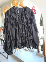 Blusa blanca traslúcida con mangas largas acampanadas con volados. Escote en V.