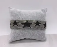 Pulsera tejida con pequeñas cuentas de colores rojo y dorado, formando un patrón de estrellas doradas sobre fondo rojo.