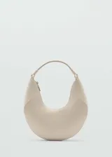 Bolso tipo hobo color crema, con asa corta de hombro y cierre de cremallera.