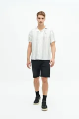 Camisa de manga corta confeccionada en lino y algodón a rayas verticales en tonos blanco, gris y beige. Tiene cuello tipo cubano, corte regular y logo bordado en el pecho.