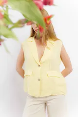 Chaleco color amarillo pastel de lino, sin mangas, con cuello solapa y cierre frontal con dos botones.