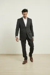 Traje de poliéster negro, corte regular fit, compuesto por saco con solapa de muesca, cierre de dos botones, bolsillos con solapa y pantalón de vestir con bolsillos laterales y traseros.