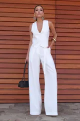 Chaleco blanco con escote en V, corte entallado, botones forrados y hebilla ajustable en la espalda.