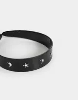 Vincha rígida negra con apliques de glitter plateado en forma de lunas y estrellas.