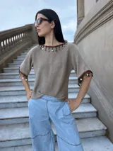 Remera tejida color beige de algodón con mangas cortas y apliques de lentejuelas en cuello y mangas.