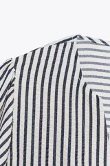 Blusa de cuello redondo con escote pico y manga corta abullonada acabada en elástico. Cierre frontal con lazos. Diseño a rayas verticales blancas y negras.
