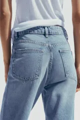 Pantalón de jean celeste de tiro alto, corte mom fit, largo regular y roturas en las rodillas.